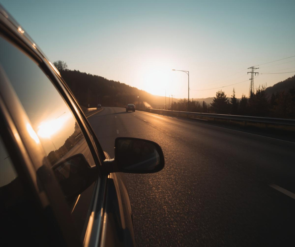 a scenic view from inside a moving vehicle traveling on a highway during sunset.