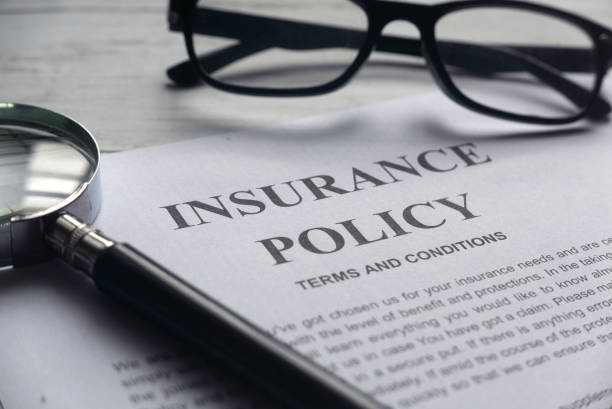 An insurance policy document on a table, accompanied by glasses and a magnifying glass for reading assistance